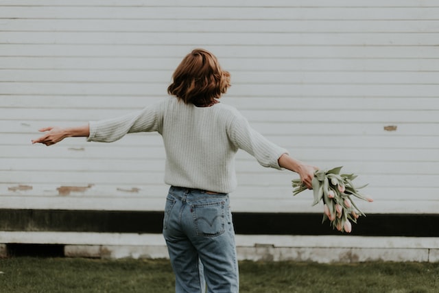 a woman with open arms holding flowers after addiction recovery