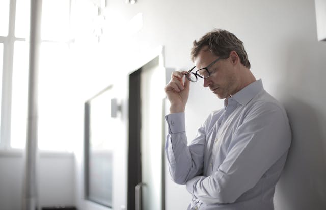 A man in a white shirt leaning against a wall