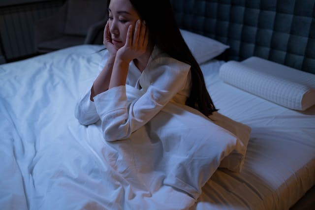 A woman sitting in her bed during nighttime