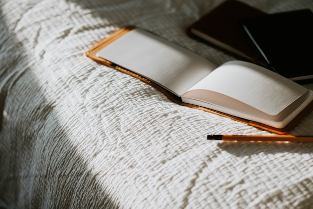 An open journal and a pen on a bed.