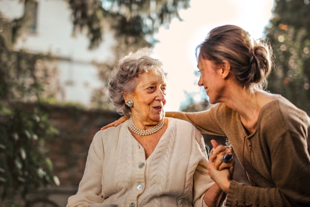 An older lady and her granddaughter holding hands and smiling