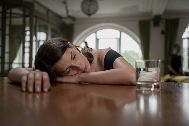 A depressed woman resting her head on the table surface