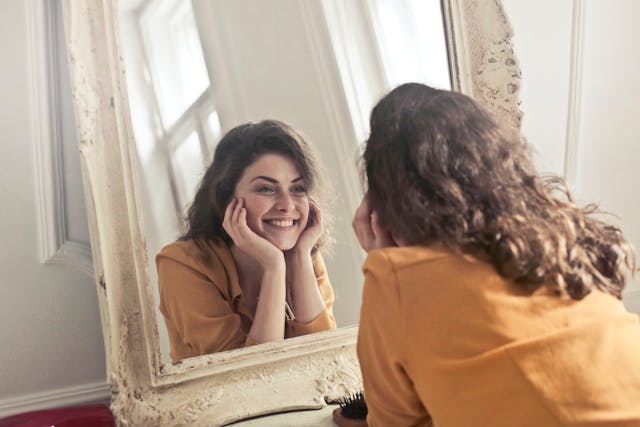 A happy woman looking at herself in the mirror